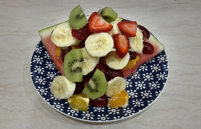 Watermelon slice with bananas, kiwi, grapes, and strawberries